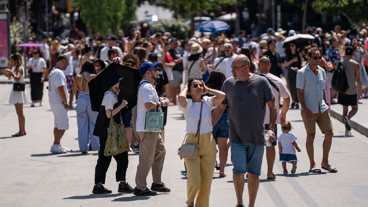 Turiștii vizitează Sagrada Familia protejându-se cu sticle de apă, evantaie, pălării și ventilatoare portabile în timpul unei valuri de căldură în Barcelona, Spania, pe 15 august 2025