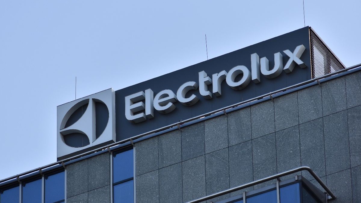 Fotografie a exteriorului unei clădiri de birouri cu logo-ul „Electrolux” în alb pe fond albastru închis. Fațada clădirii este compusă din panouri gri, texturate, cu ferestre din sticlă reflectorizantă.