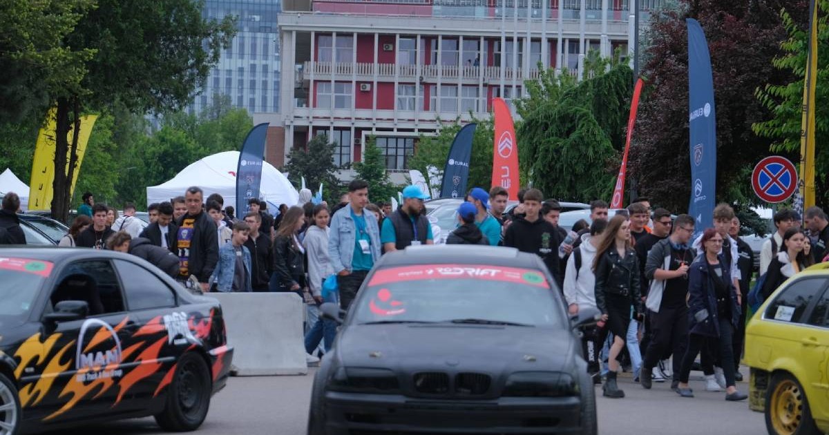 Fotografie din cadrul POLI AutoFest, unde sunt două mașini modificate și un grup numeros de tineri, în mare parte adolescenți și studenți.