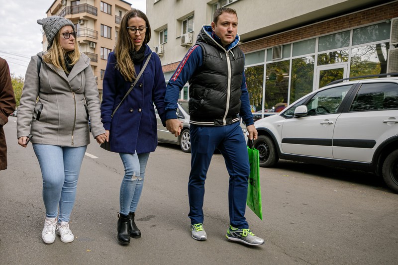 Elena își analizează fiecare pas când merge. Se uită în jos, în timp ce îi ține de mână pe Adrian și pe Andreea, o prietenă de familie. Foto: Eli Driu