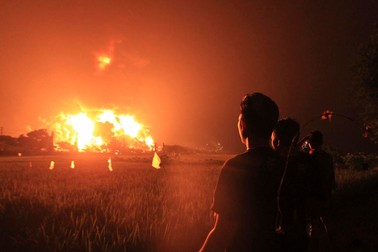 epa09104158 People look at the burning oil refinery during a fire at a state run Balongan oil refinery in Balongan, Indramayu, Indonesia, 29 March 2021. At least five people had been injured and hundreds of people have been evacuated, according to the oil company operator Pertamina. EPA-EFE/STR