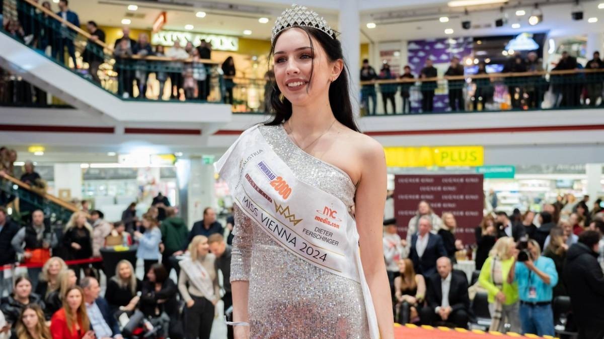 Miss Vienna 2024, Lucia Sisic, la evenimentul Miss și Mister Vienna, în rochie strălucitoare argintie, cu coroană pe cap, multă lume se vede în spate