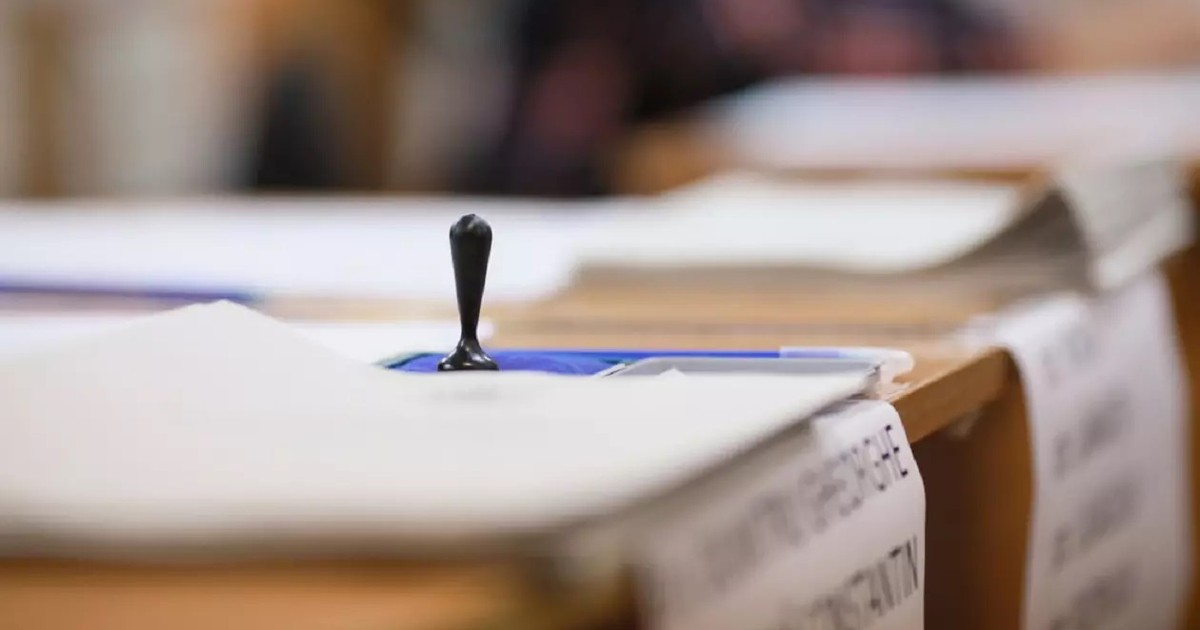 O stampila se afla pe un birou intr-o sectie de votare, iar langa ea se vad mai multe hartii