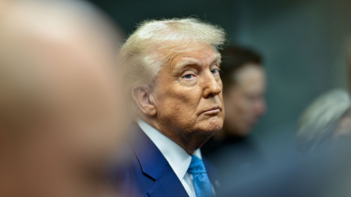Donald Trump, președintele SUA, în prim plan, îmbrăcat într-un costum de culoare albastră, cu o cămașă albă și o cravată de culoare albastră