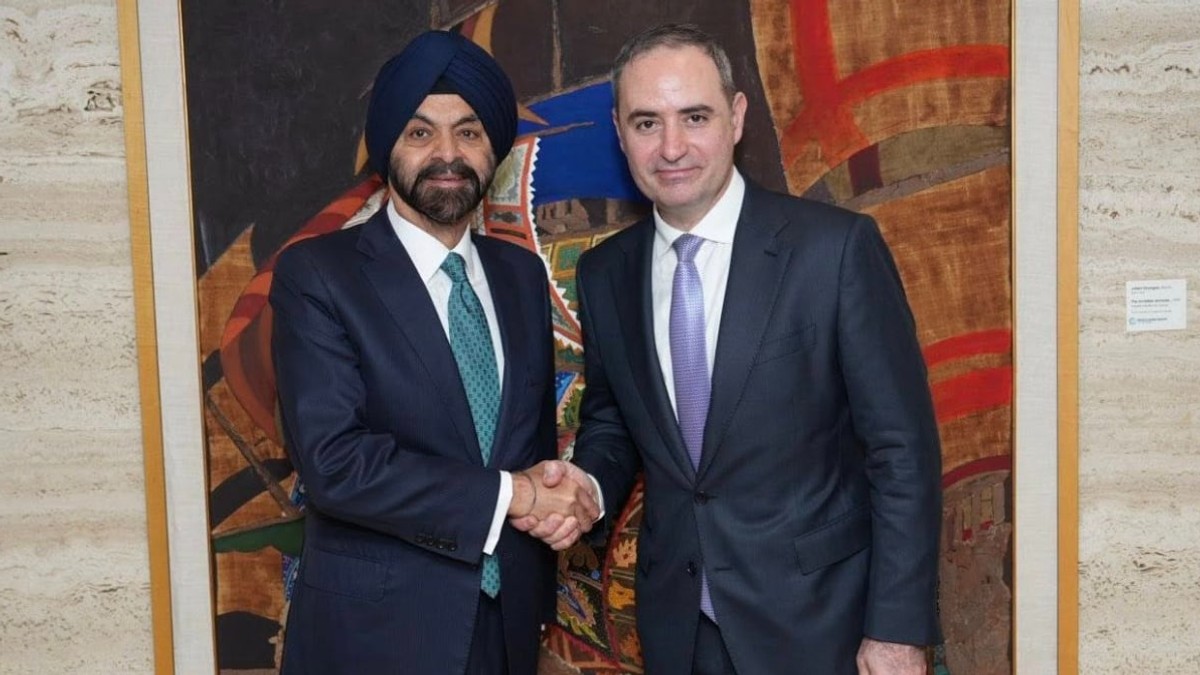 Imaginea surprinde doi oficiali îmbrăcați în costume, strângându-și mâna într-un gest formal, semn al unei întâlniri diplomatice sau al unui acord. Contextul și expresiile lor sugerează o colaborare sau un parteneriat între cele două părți.