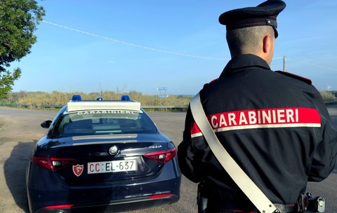 Un politist italian pe o autotradă, lângă o mașină de carabinieri, în timp ce controlează traficul