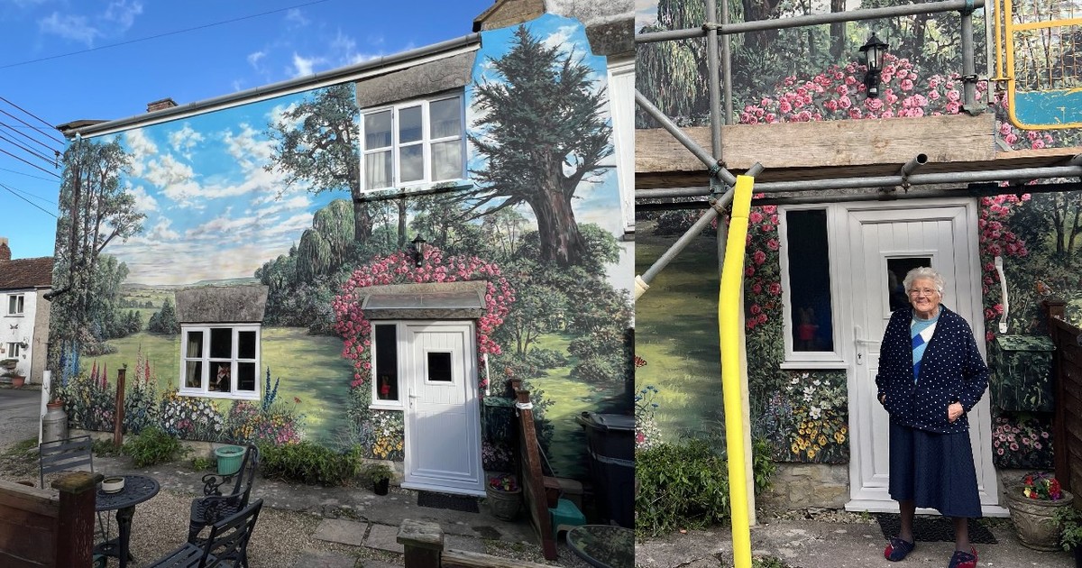 O femeie de 94 de ani, lângă casa sa care e pictată
