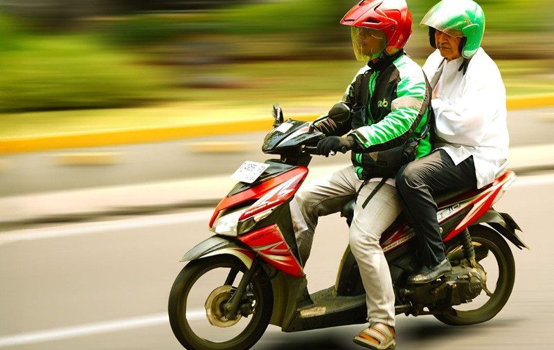 Doi oameni pe un scuter merg pe strada