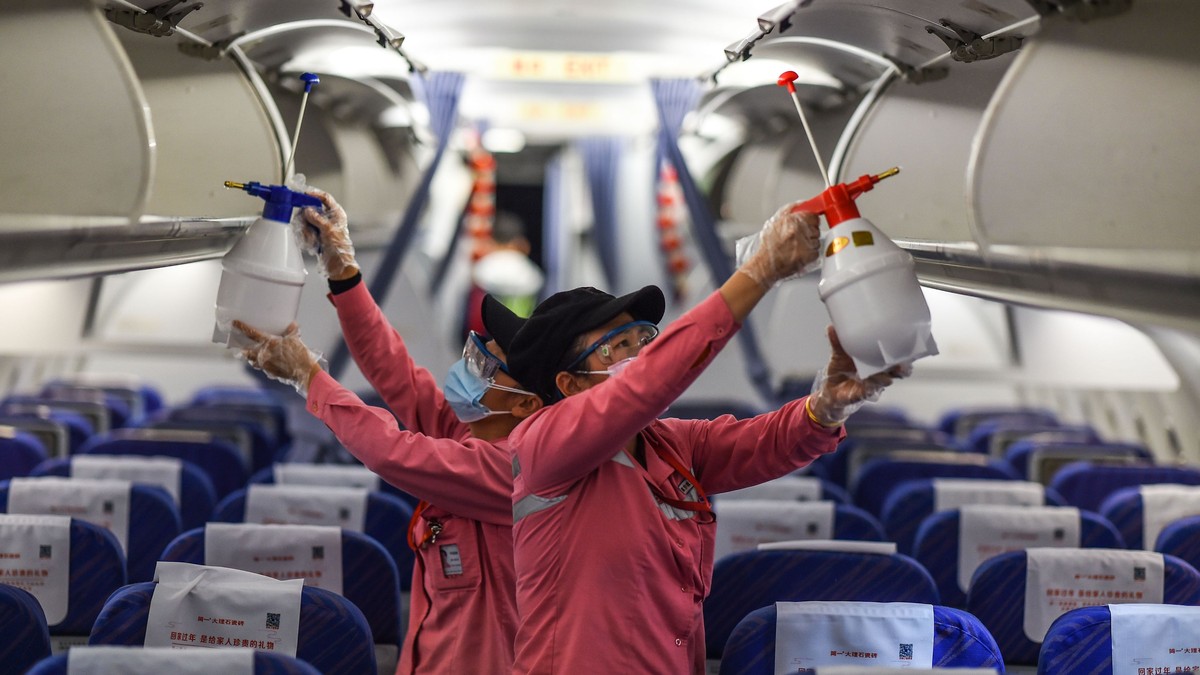 Doi membri ai unei echipe de curățenie dezinfectează interiorul aeronavei înainte de un nou zbor