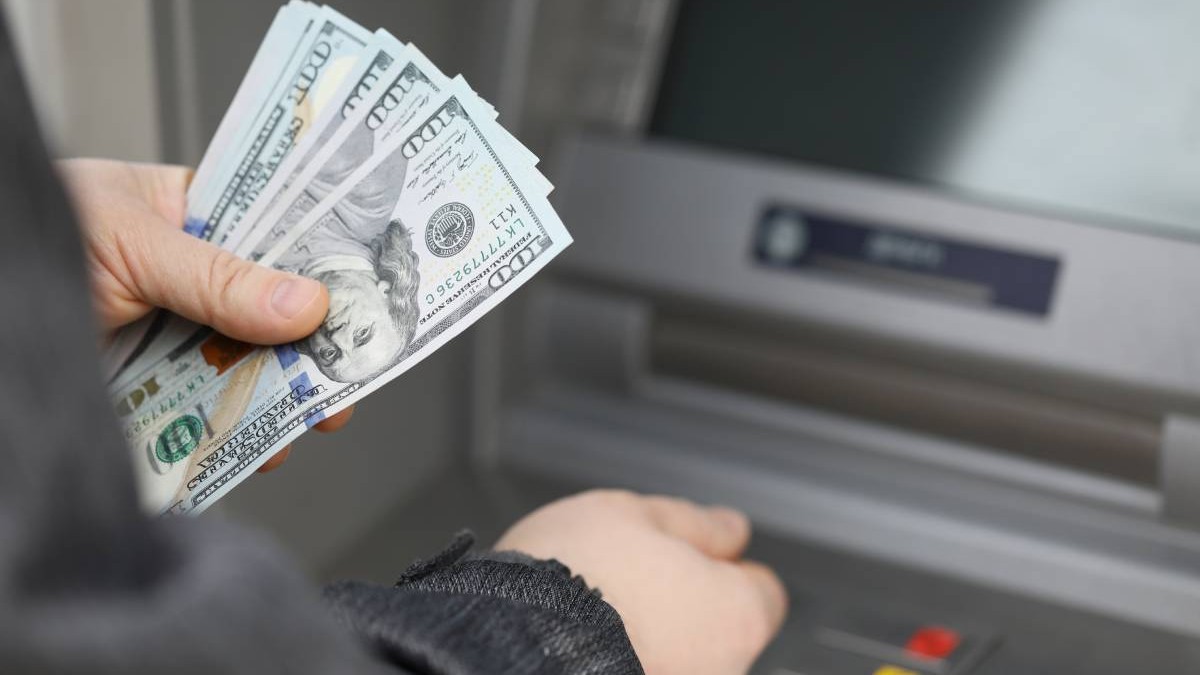 Un bărbat retrage numerar pe stradă de la un bancomat