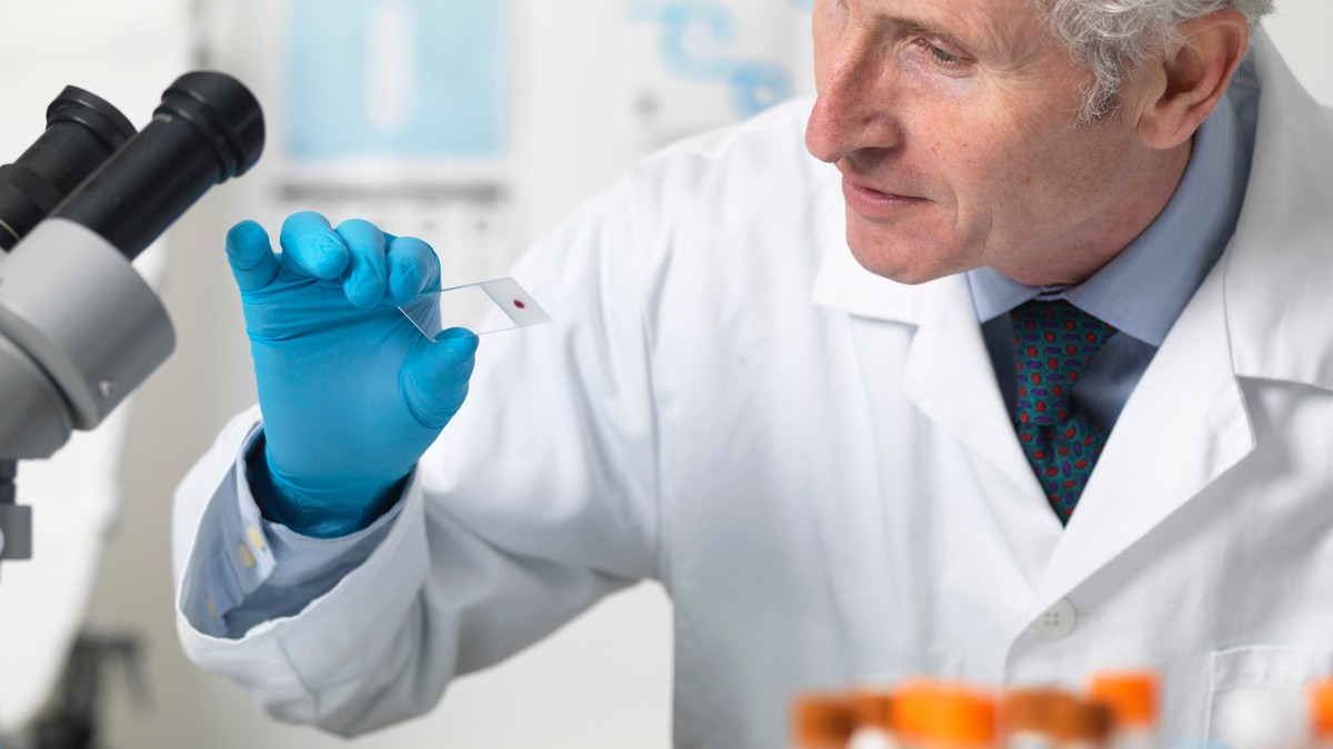 Medic care examinează la microscop sângele pacienților și alte probe în vederea testării