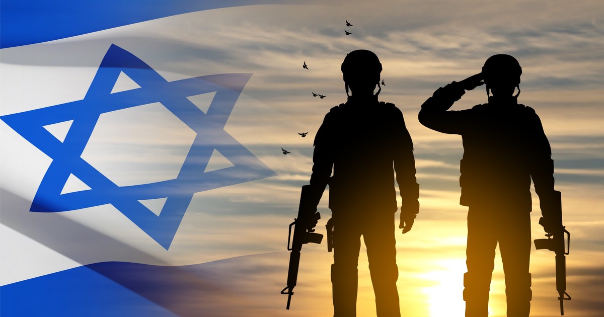 Ce înseamnă serviciul militar obligatoriu în Israel - Imagine în contralumină cu doi soldaţi alături de steagul Israelului,