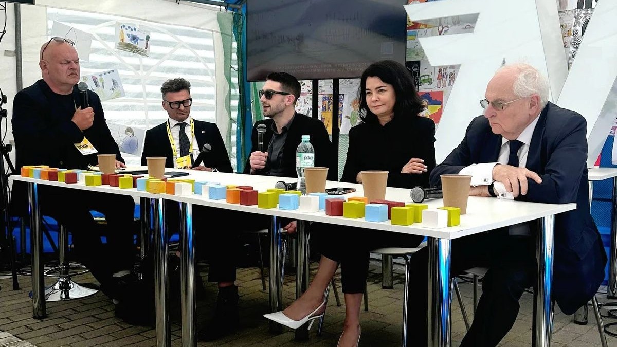 Patru bărbați și o femeie stau la o masă și discută
