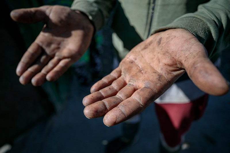 Mâinile muncite ale unui bărbat care lucrează cu ziua pe câmp