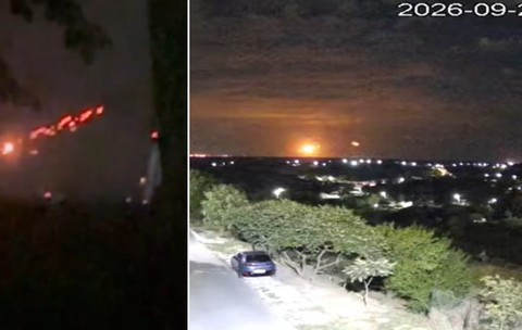 Imaginea prezintă în două cadre nocturne lumini roșiatice de trasoare pe cer și o explozie luminoasă la orizont deasupra unei localități.   