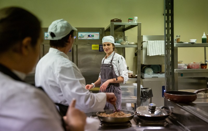 În bucătărie, fiecare își știe locul: cineva toacă legume, cineva le călește, altcineva se ocupă de carne. La o săptămână, se rotesc, ca să „nu se plictisească”