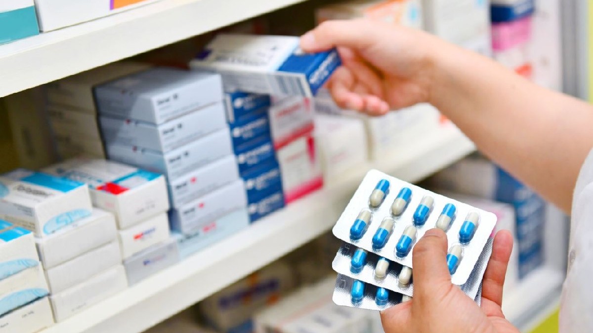 O femeie așează pe un raft mai multe tipuri de medicamente