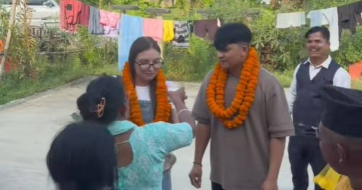 Cuplul format din nepalez (în dreapta) și soția româncă (în stânga) când ajung în curtea casei din Nepal, sunt așteptați de mai mulți nepalezi îmbrăcați elegant și au la gât câte două ghirlande de flori portocali