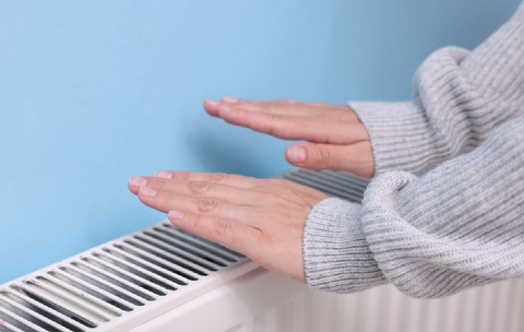 Femeie încălzindu-și mâna lângă radiator interior, closeup