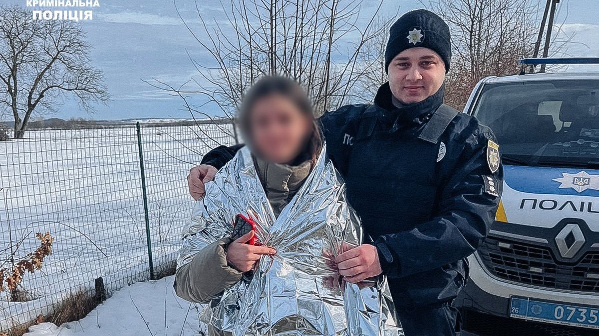 Salvată după ce a fost răpită de pe stradă, o fată de 13 ani stă alături de un polițist, la Cernăuți, Ucraina, februarie 2026