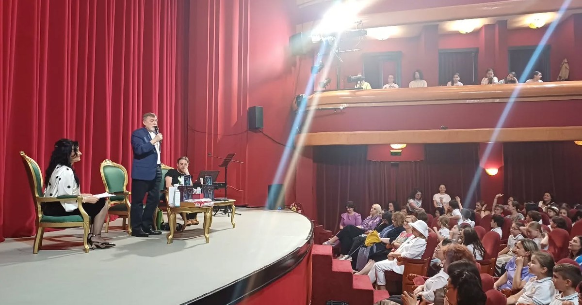 Un scriitor vobind de pe o scena despre carti copiilor, intr-o sala de teatru