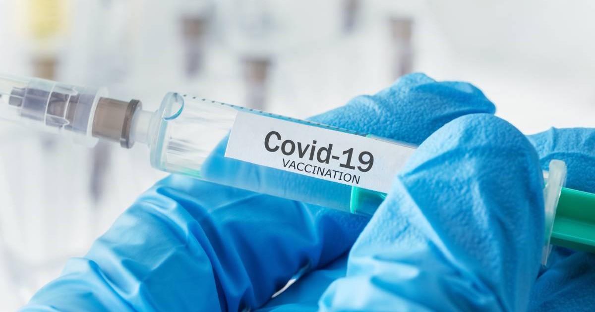 Un medic care ține în mână o mânușă cu o seringă în care este serul unui vaccin anti-COVID