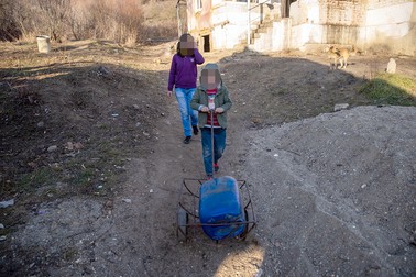 Alexandra și Daniel, în curtea casei, se duc după apă