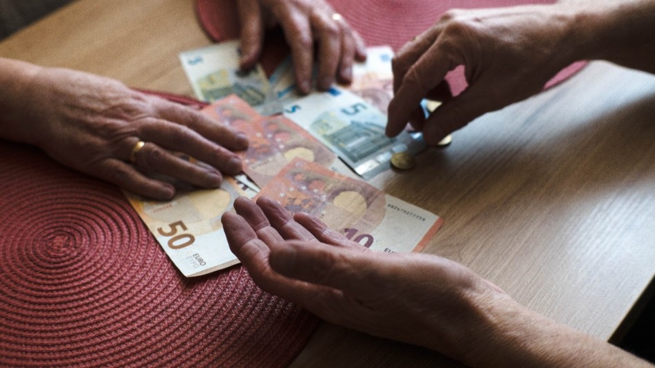 Doi bătrâni care numără bancnote euro