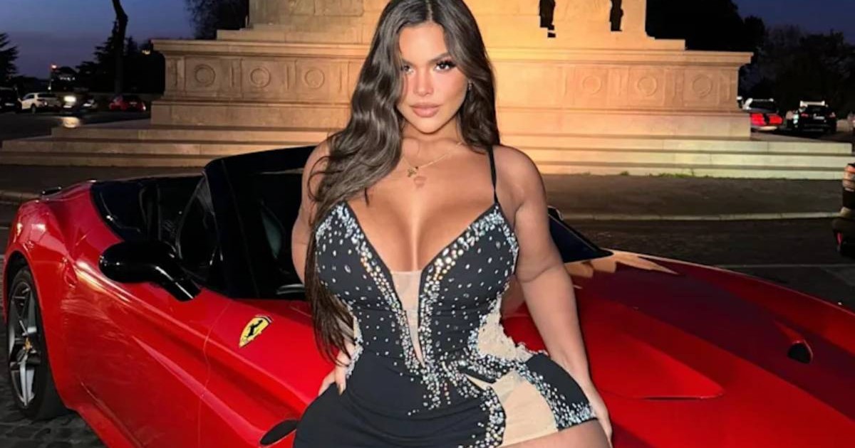 tanara imbracata intr-o rochie neagra rezemata de o masina rosie ferrari