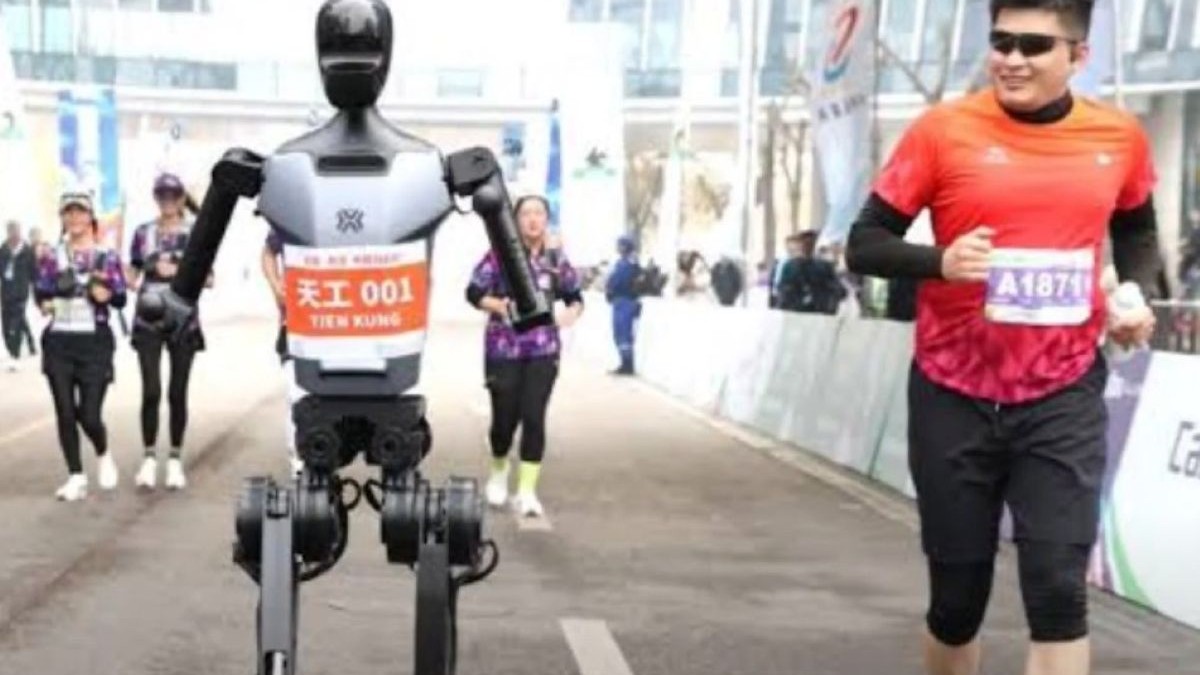 Un robot umanoid și un om trec linia de sosire la o competiție sportivă. Tânărul se uită cu admirație către oponentul său