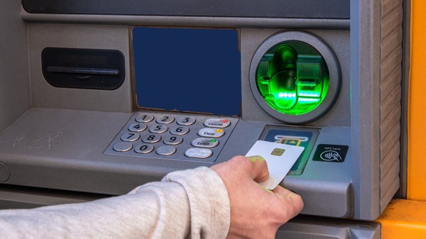 Un bărbat care scoate bani din bancomat