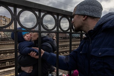 Oleg (dreapta), care a decis să rămână în Irpin, îi mângâie pe fiul Maksim și pe soția sa Yana, înainte de sosirea unui tren de evacuare în orașul Kiev, la gara din Irpin, Ucraina, 4 martie 2022. Foto: EPA