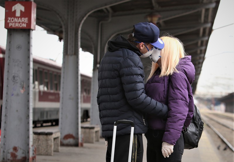 Doi tineri se sărută prin măști pe un peron din Gara de Nord