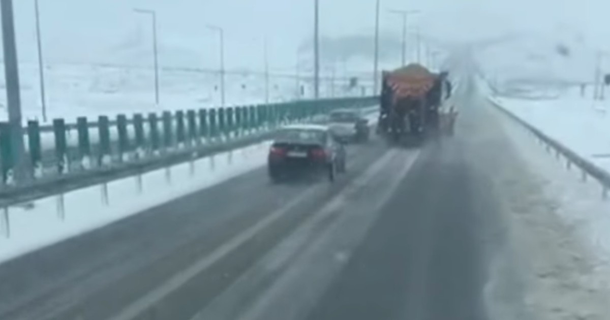 Mașini care circulă pe șosea în timp ce ninge