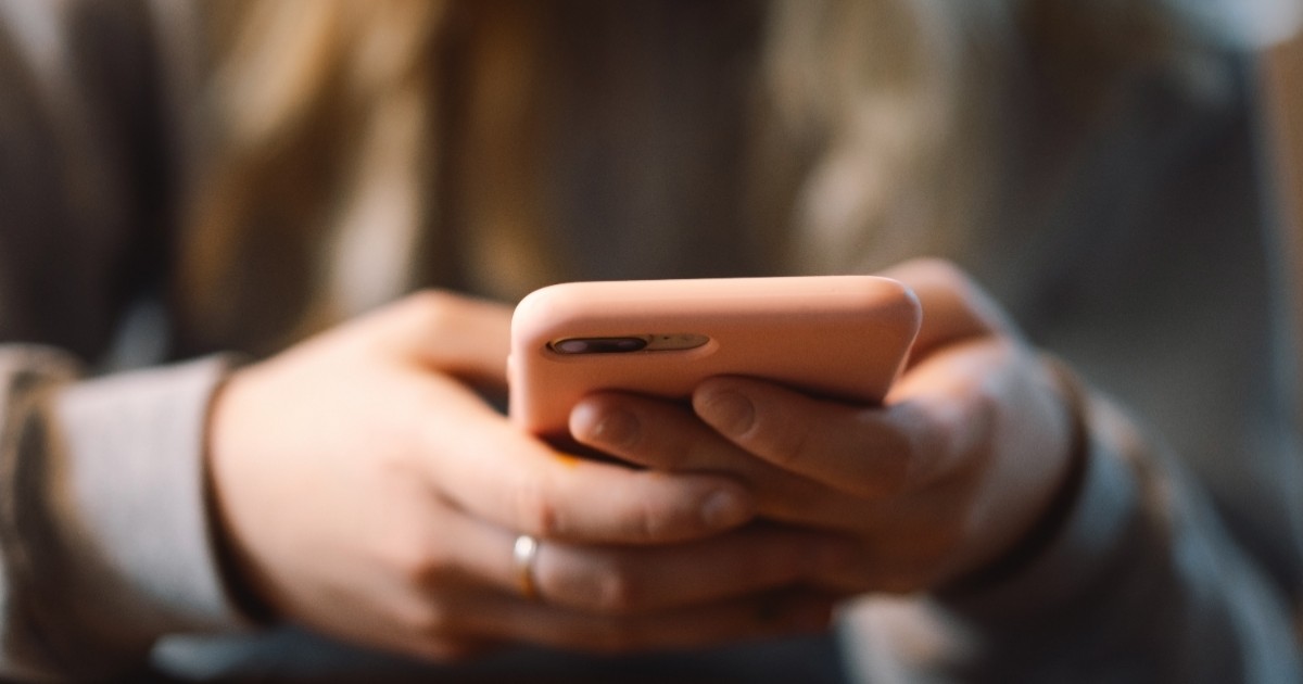 o femeie care ține un telefon în mână și se uită la mesaje