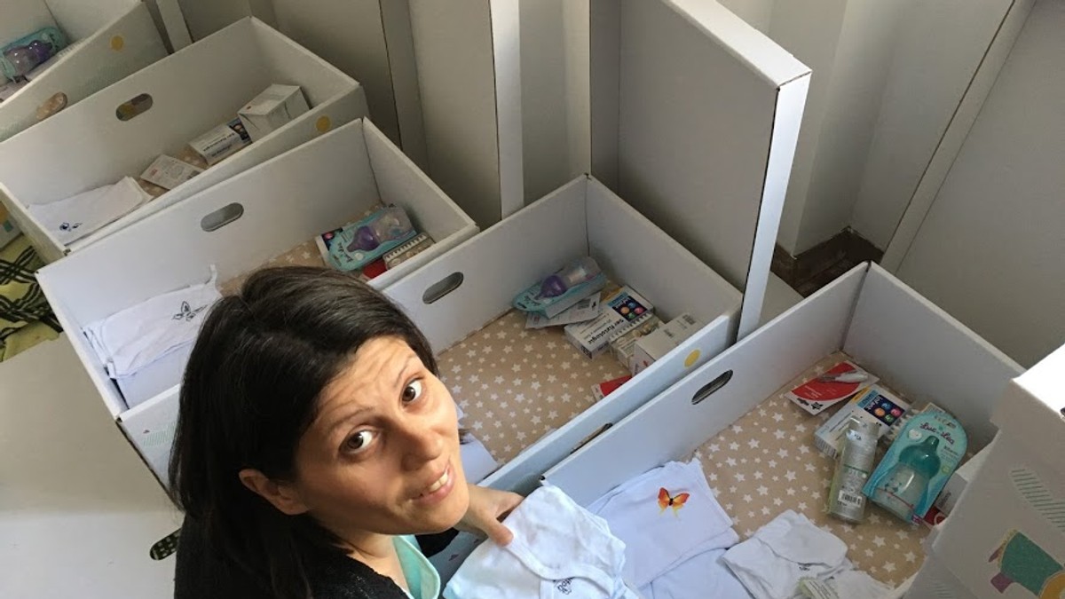 Marinela Rață Panaite, femeia care a adus Dodo Baby Box în România. Marinela Rață privește în sus și are în față mai multe baby box