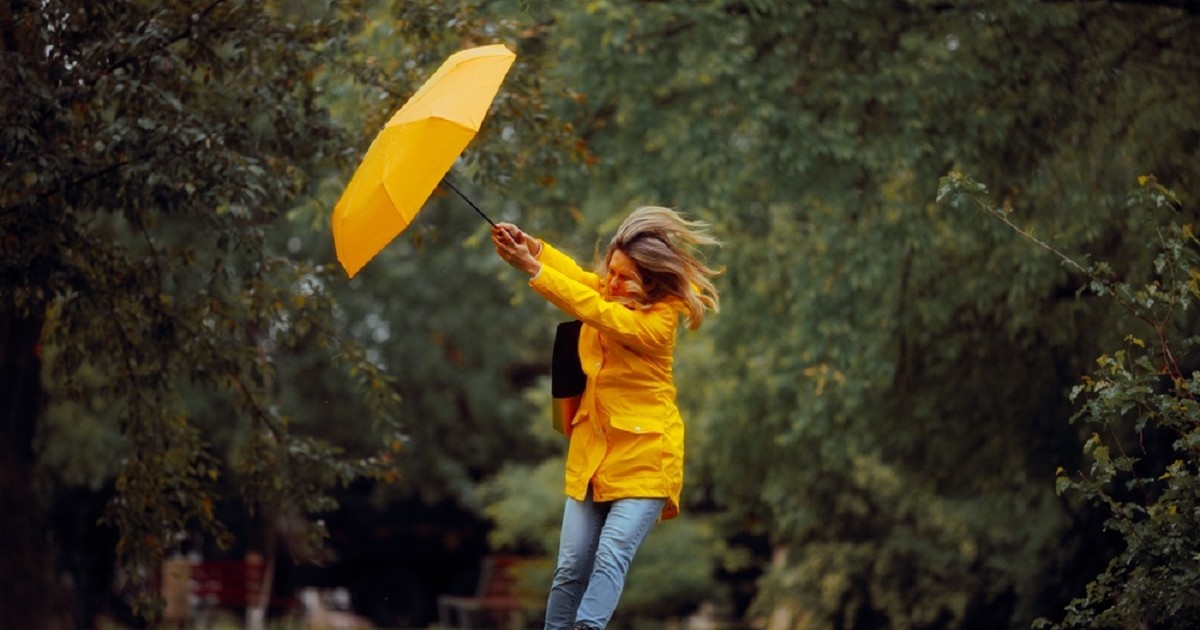 Ce înseamnă când visezi umbrelă - Imagine cu o femeie care îşi ţine cu greu umbrela pe furtună