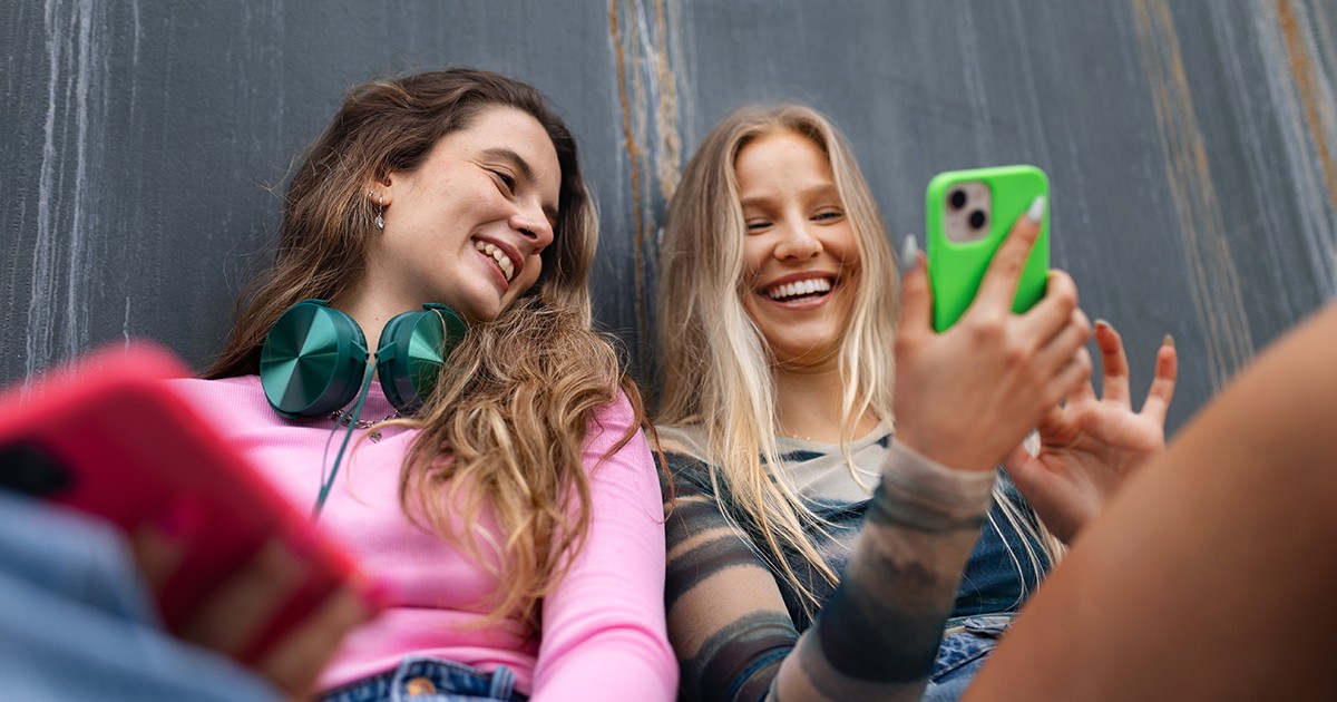 Doua tinere vesele se uită in telefoane