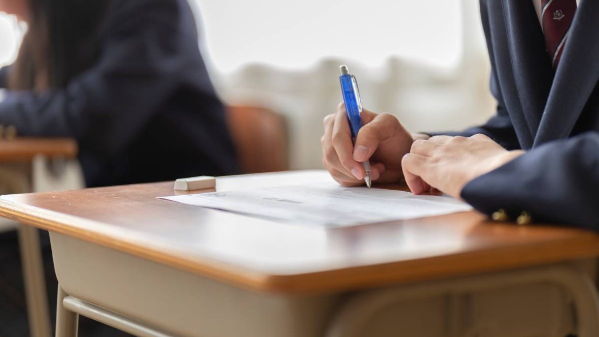 Un elev cu pixul în mână, în timp ce stă în bancă și rezolvă subiectele pentru examenul de Evaluare Națională 2025