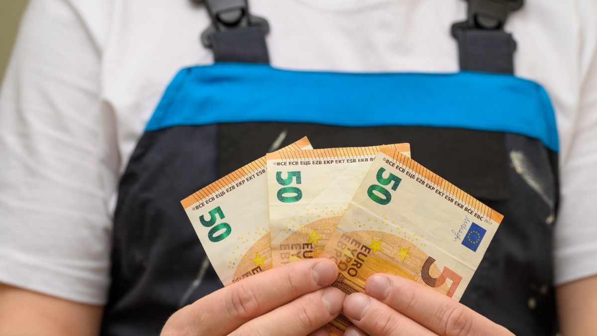 Muncitor în construcții care ține în mâini bancnote de 50 de euro