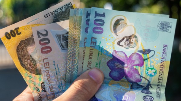 Mână ținând bani românești. Bancnote românești de 100 și 200 de lei ținute în mână