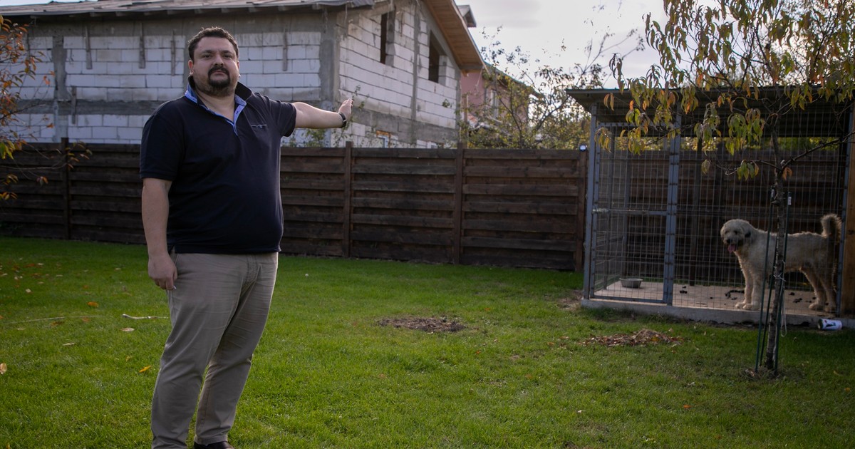 Andrei Dumitrescu ține un Ciobănesc mioritic lângă gardul peste care se vede vila ridicată de vecini