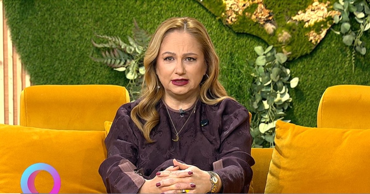 Astrologul Cristina Demetrescu stă pe o canapea portocalie, cu un decor verde în spate