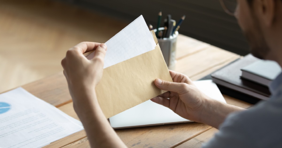 Livrare document. Un tânăr om de afaceri stă la birou și ține plicul cu o scrisoare în mâini