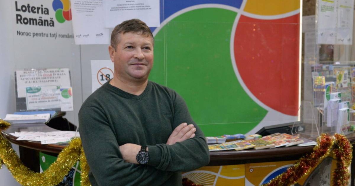 Câștigătorul la Loto, îmbrăcat într-o bluză de culoare verde închis, cu mâinile încrucișate, în sediul Loteriei Române
