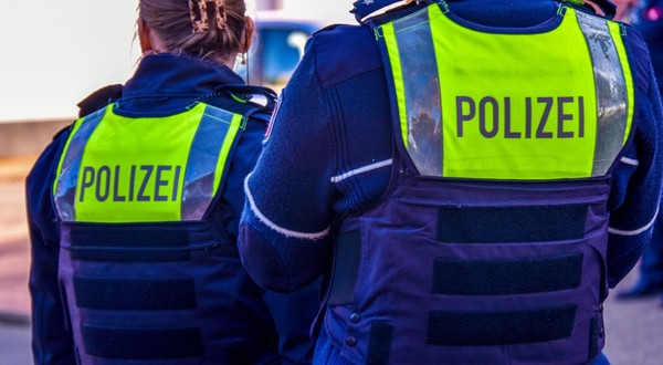Polițiști în Germania, o femeie și un bărbat care stau cu spatele, poartă veste antiglonț și inscripția POLITZEI