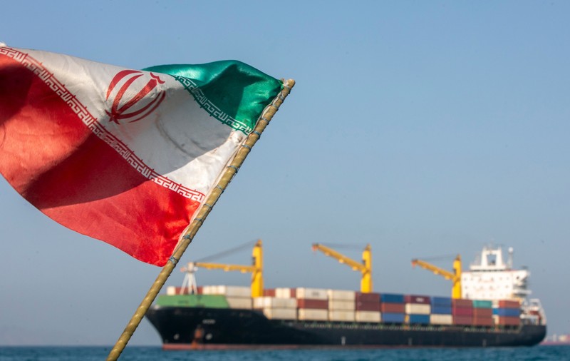 Un steag iranian flutură în vânt în timp ce navele rămân ancorate pe 16 mai 2026 în Strâmtoarea Ormuz, lângă Insula Larak, Iran.