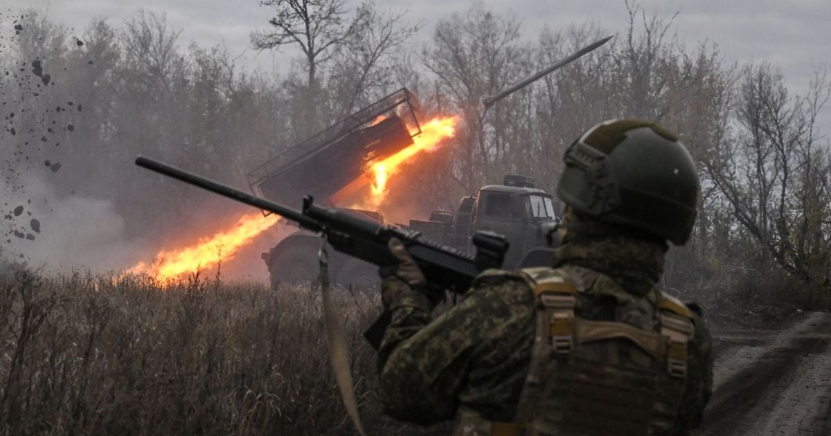 Un soldat rus stă cu arma în mână și privește spre un un lansator multiplu de rachete BM-21 Grad care trage spre poziții ucrainene din sectorul Pokrovsk al liniei frontului, octombrie 2025