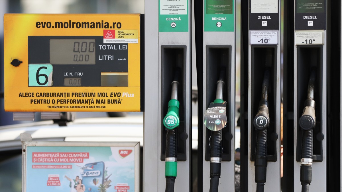 Imaginea prezintă detaliul unei pompe de alimentare dintr-o stație de carburanți, evidențiind pistoalele pentru benzină și motorină alături de ecranul digital de afișare a costului și litrajului.