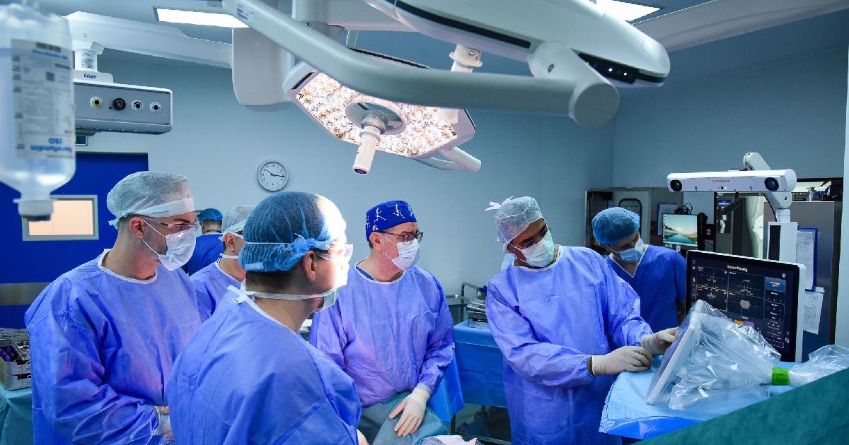 Mai mulți medici într-o sală de operație, unul privește un monitor